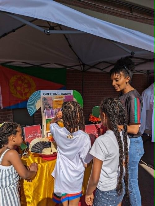 Children exploring cards at the Kab Libey booth with the founder