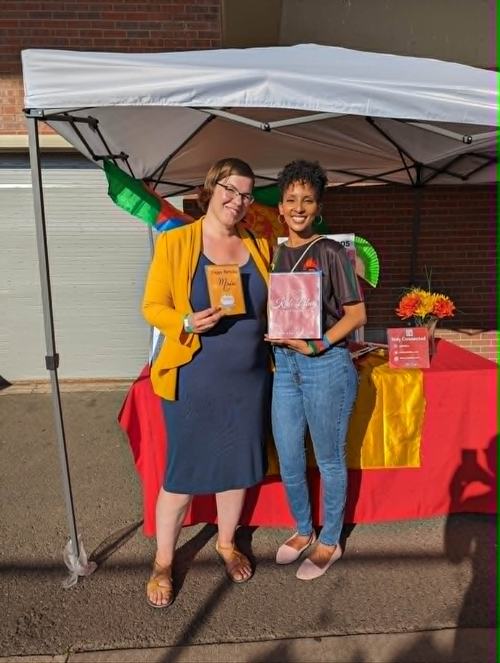 Two friends at the Kab Libey vendor tent holding cards